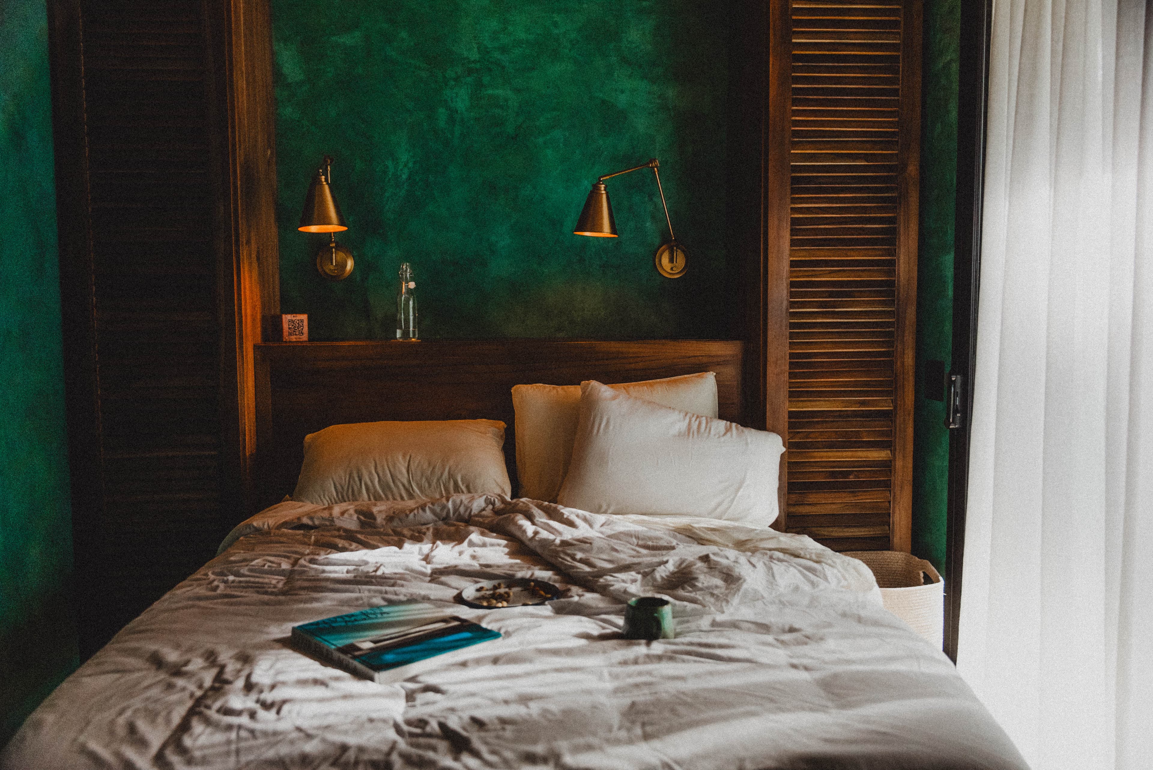 Suite bedroom with green plaster walls and brass lamps